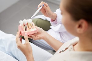 a patient holding a model of a dental implant with a dentist explaining the process